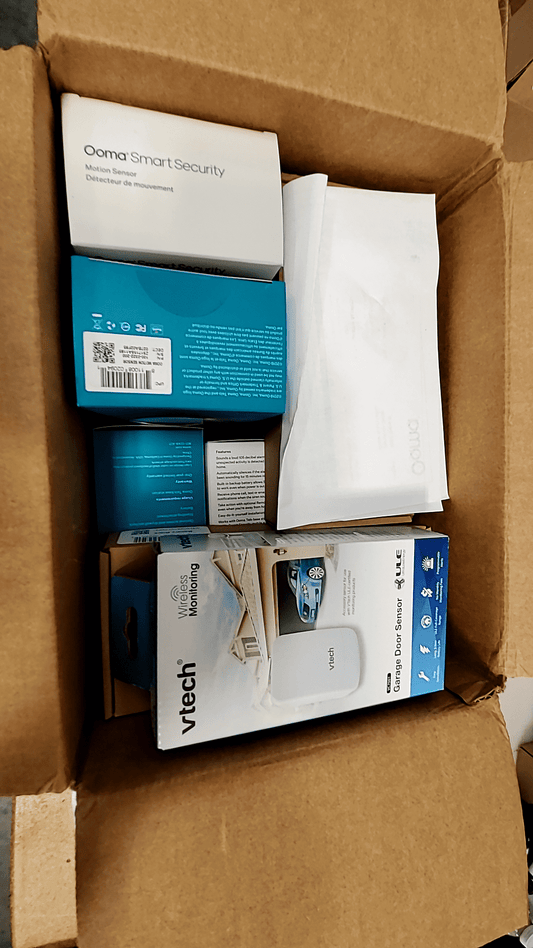 Ooma Smart Home Security System kit displayed in a cardboard box with various sensors and components.
