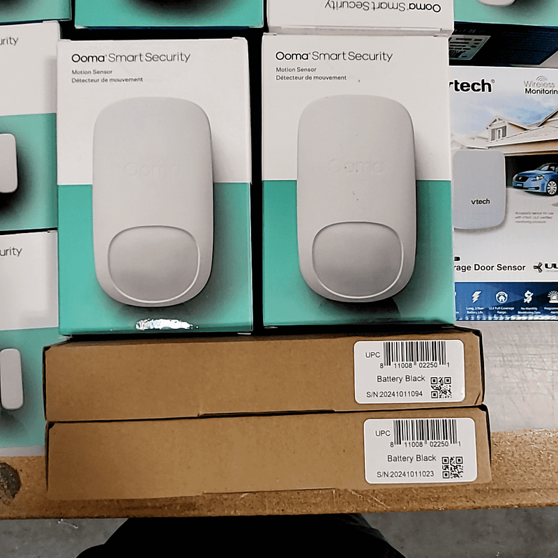 Ooma Smart Security system components with door sensors and battery packs on display.