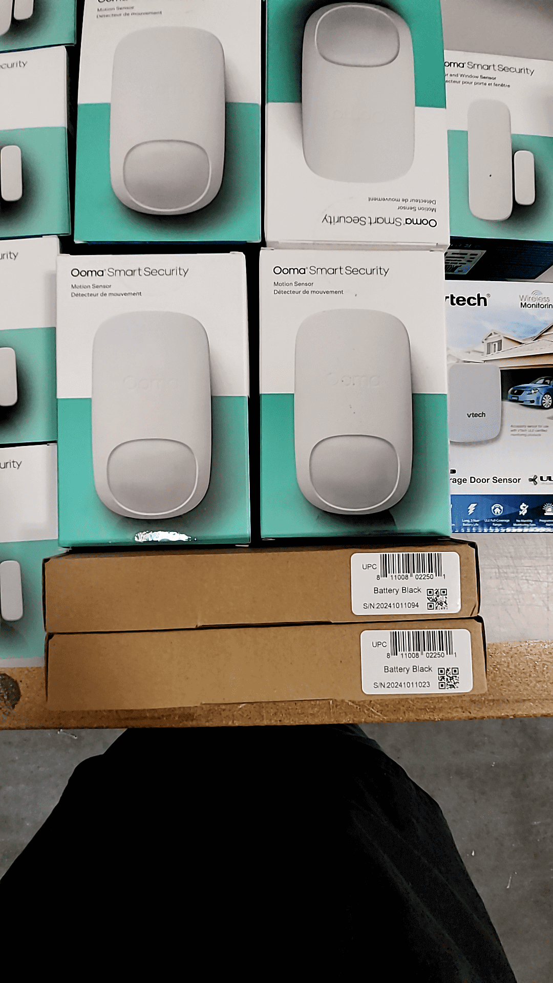 Ooma Smart Security system components with door sensors and battery packs on display.